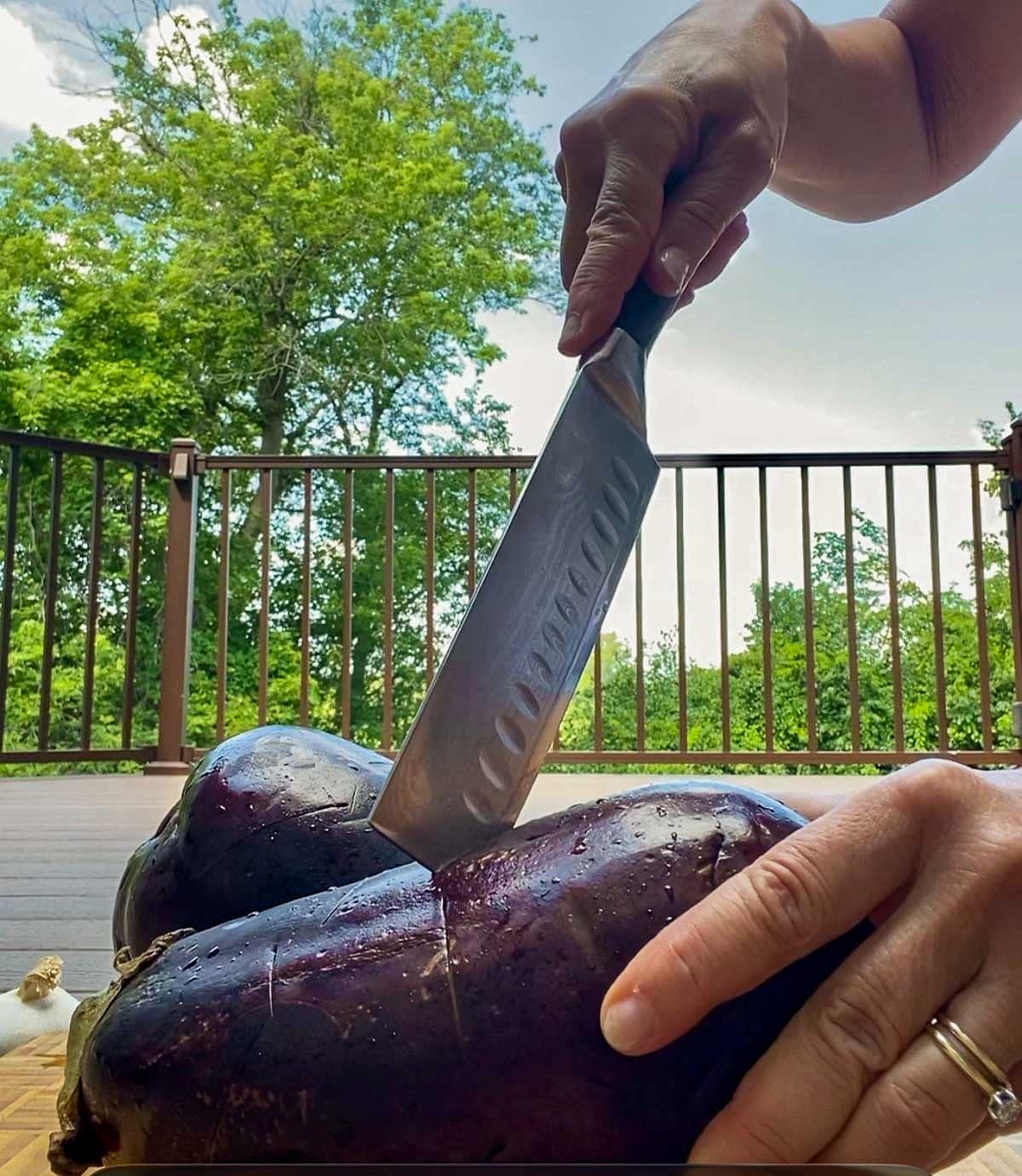 Showing how to make deep slits and cuts into the eggplant before grilling.