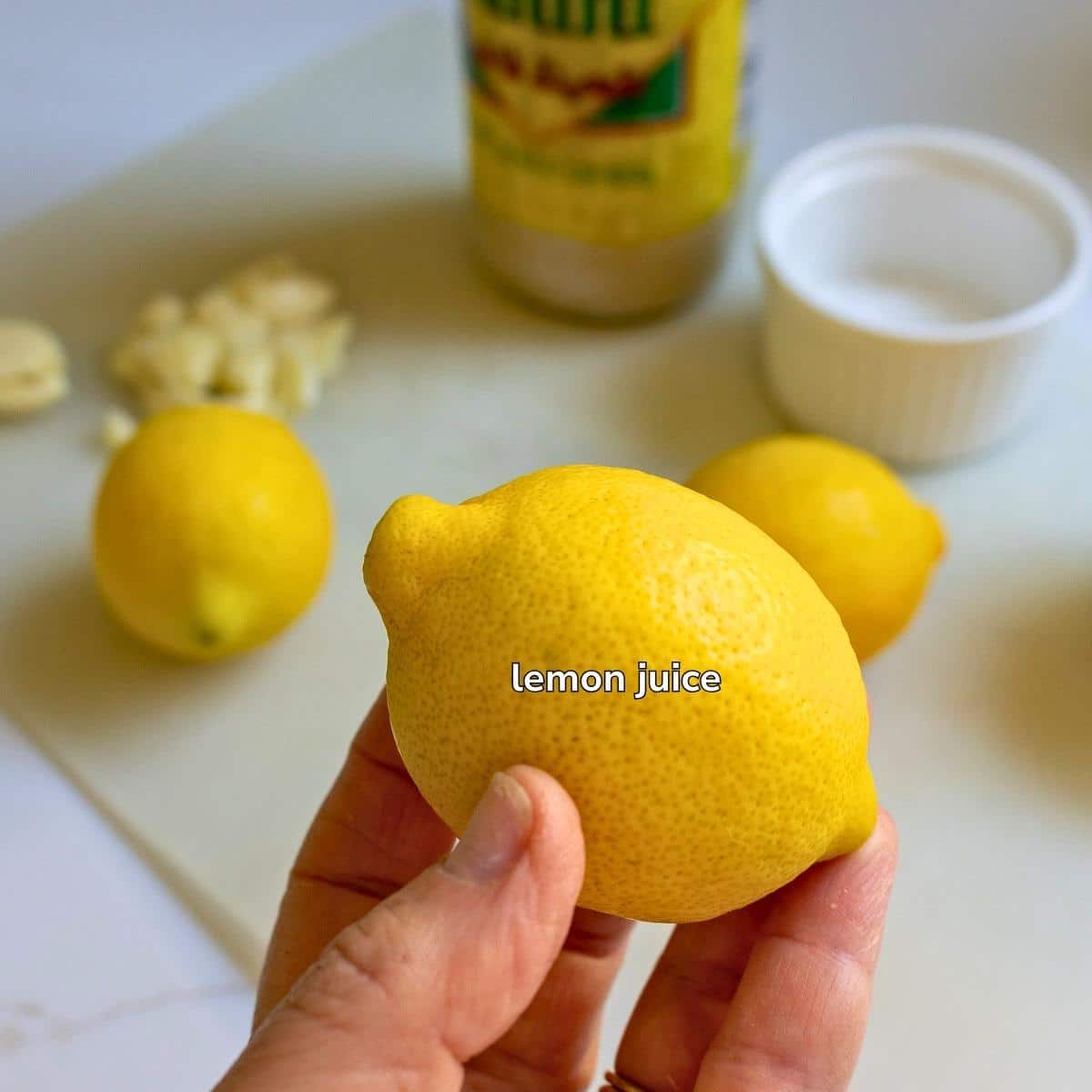 Holding a fresh whole lemon.