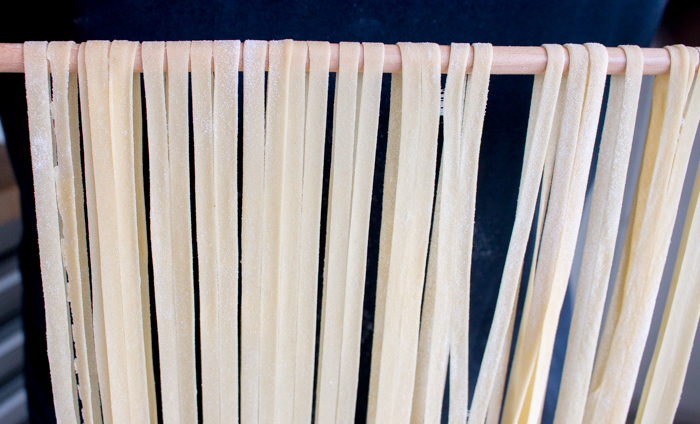 Tagliatelle pasta drying and hangin on a pole.