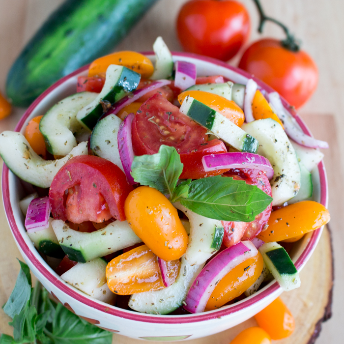 Heirloom Tomato Cucumber Salad in a white bowl showing that the vegetables are all cut about the same size to make it easier to eat.