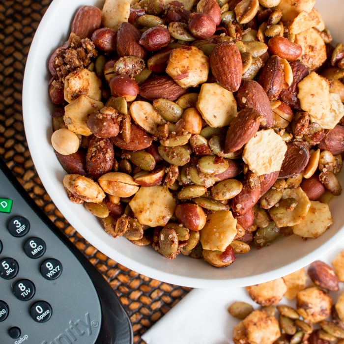 Close up of the nuts and spices in a white bowl with a remote control in the background.