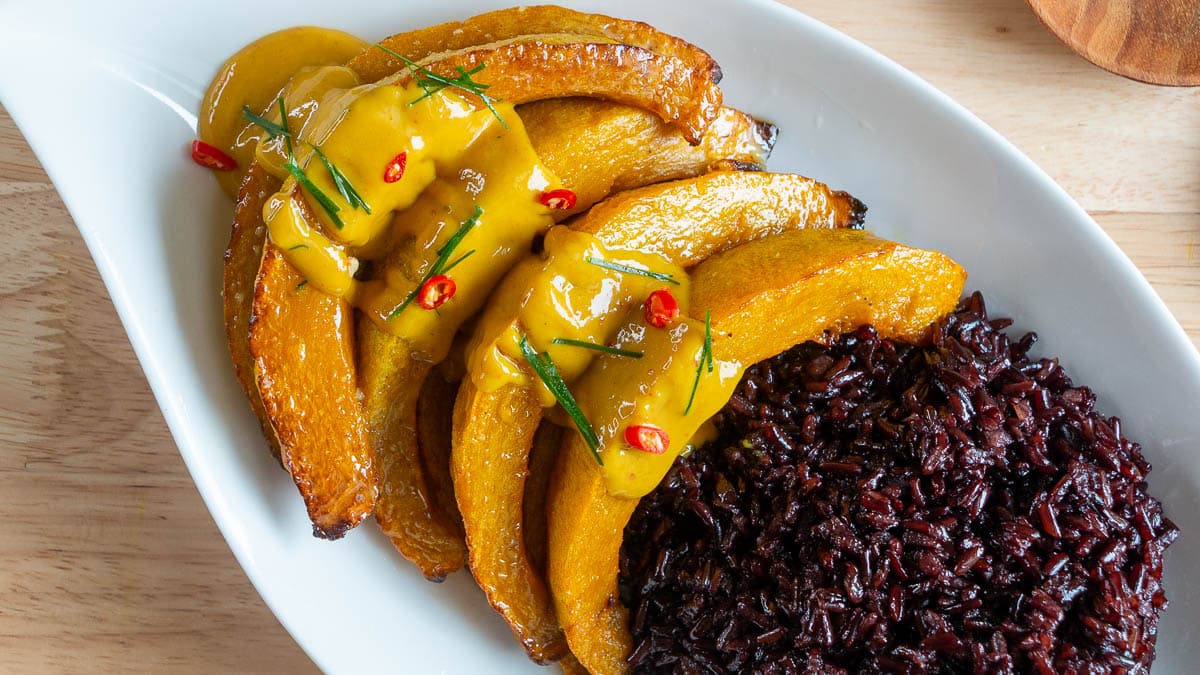 Kabocha squash curry with forbidden black rice on a white plate.