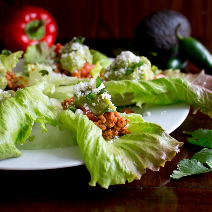 45 degree close up view of turkey lettuce wrap with avocado and red pepper props