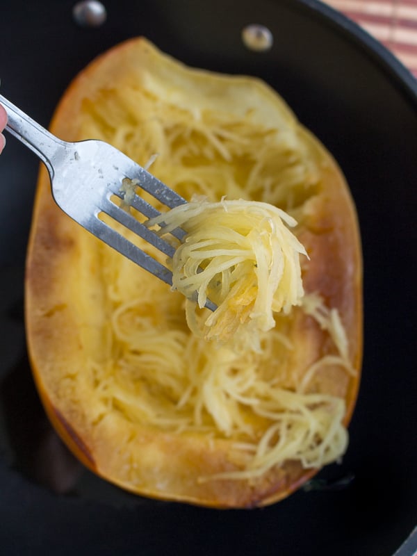 Removing the cooked long stands of spaghetti squash with fork