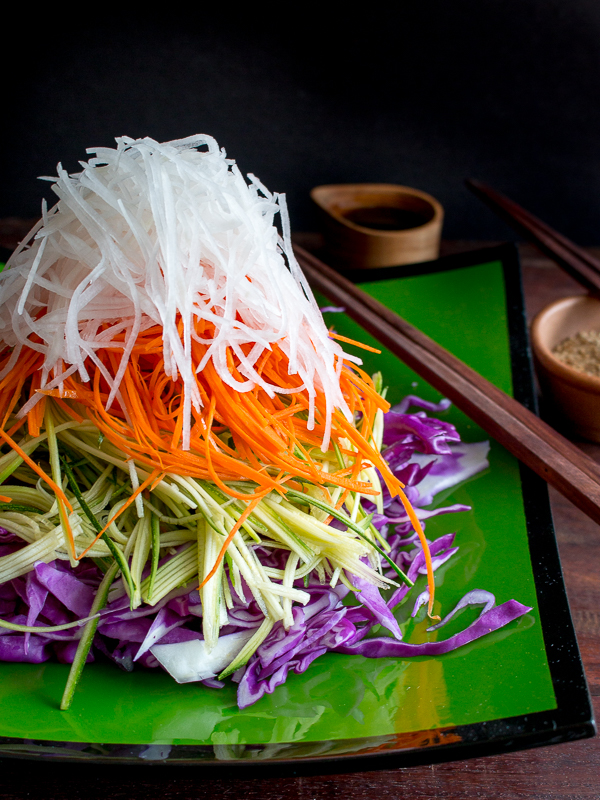 Mountain high layered Asian Salad with sesame seeds and tamari dressing on side with chopsticks