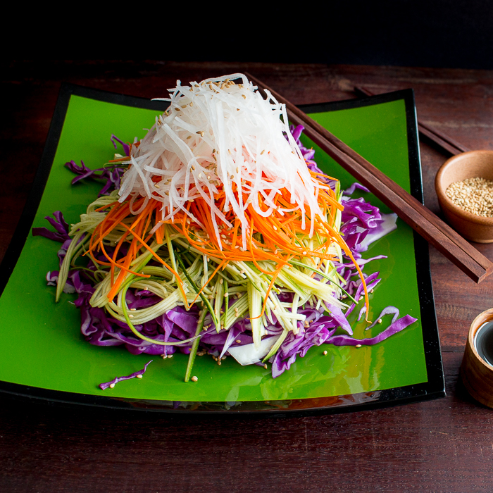 Layered Asian salad with sesame served with a side of tamari ginger dressing and sesame seeds