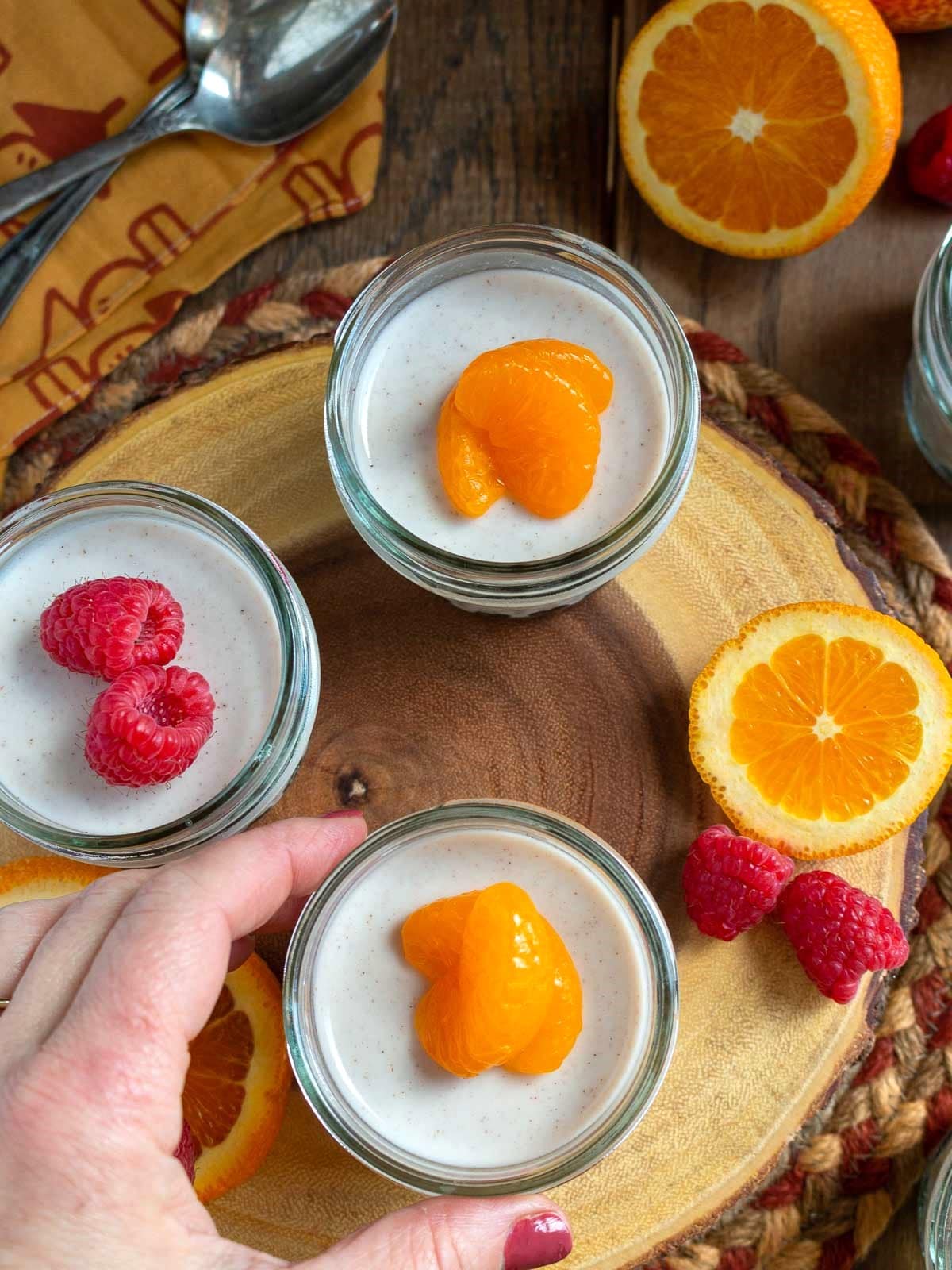 Spicy Chai Coconut Jelly cups on a wooden board with a person holding one.