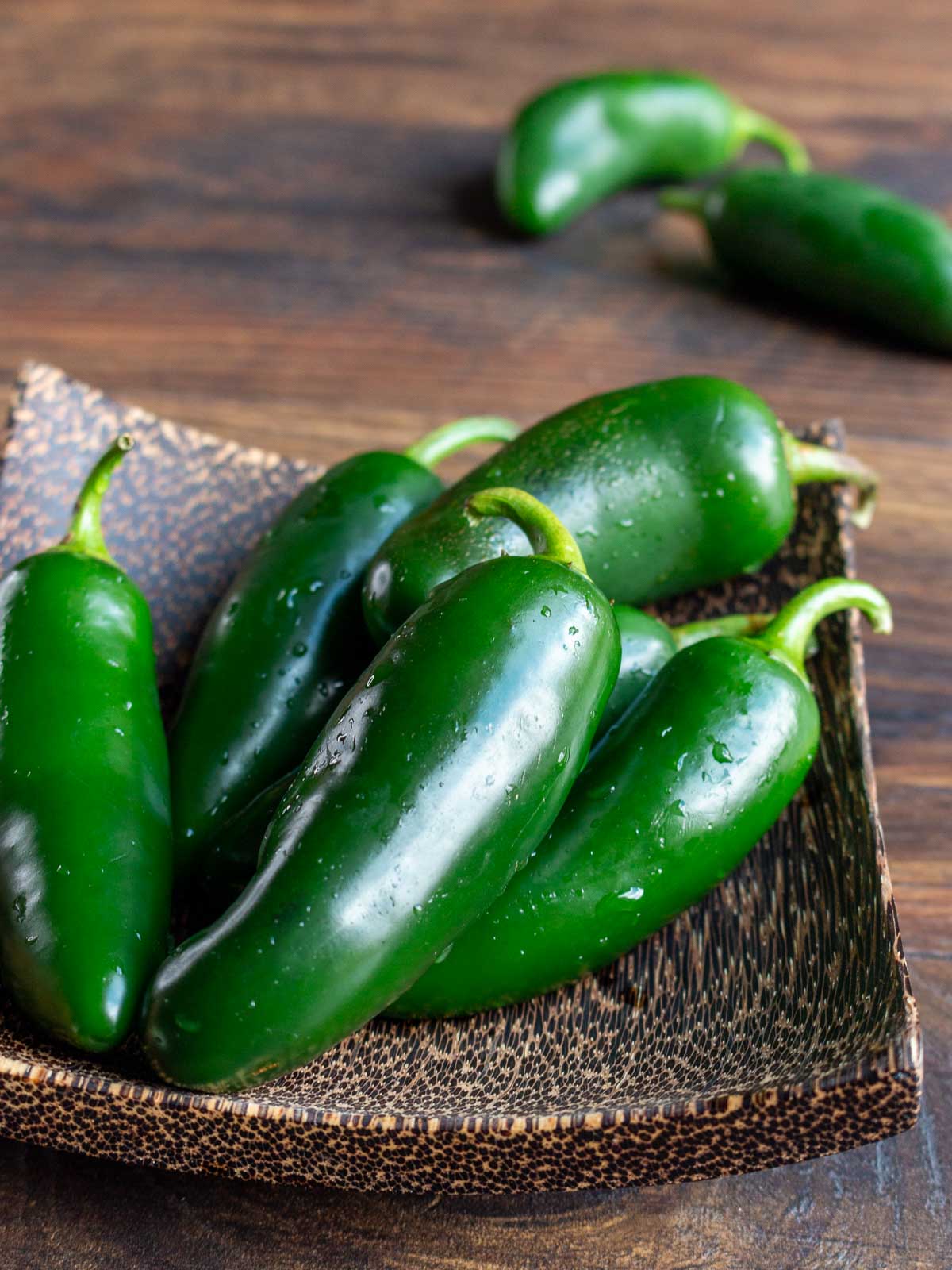 Fresh jalapenos in a wooden bowl.