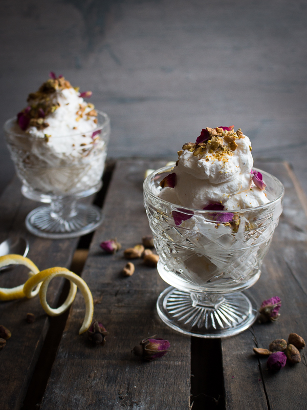 Rose and Lemon Mousse cups in glass cups with lemon zest and nuts and rose petals on the wooden table.