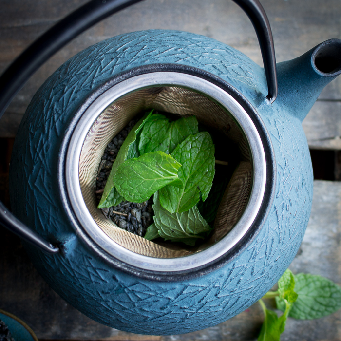 Top down shot looking into tea pot with gunpowder tea and mint leaves