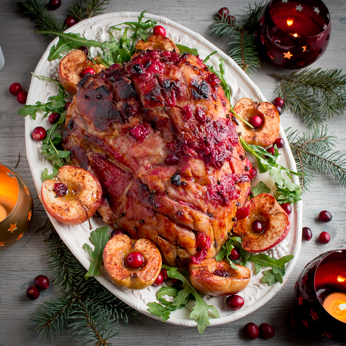 Whole Spiced cranberry Glazed ham with apples top down shot garnish and on holiday table