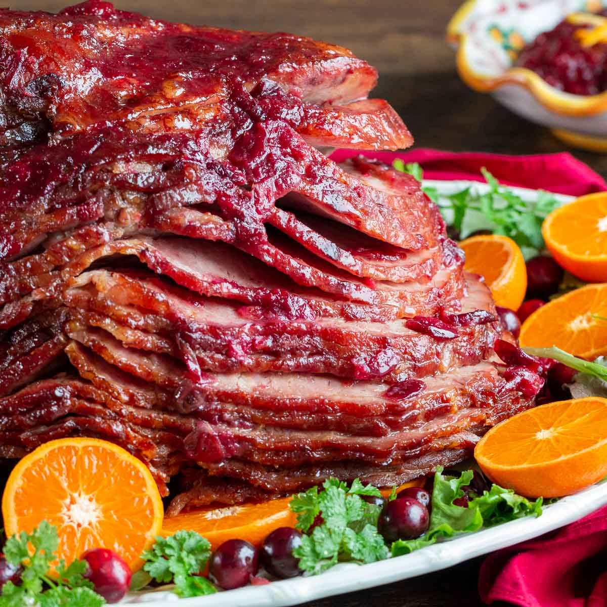 Air Fried Ham with a cranberry glaze of a serving platter with oranges and fresh cranberries.