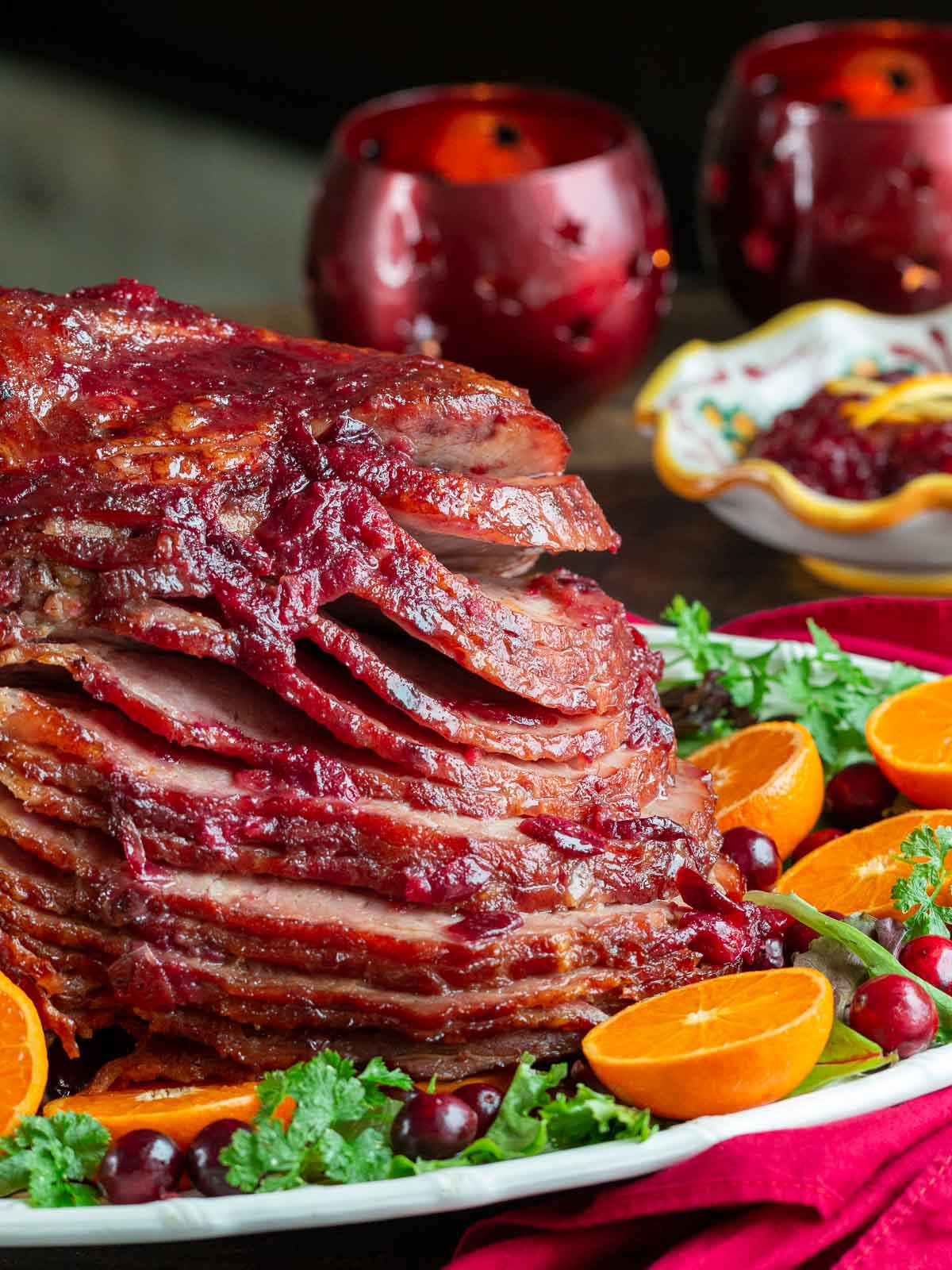 Cranberry glazed ham garnished with oranges and greens.