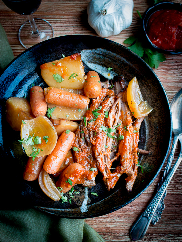 Italian Pot Roast with potatoes and carrots on a black plate.