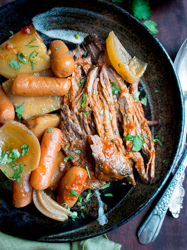 Beef, carrots and potatoes on a black plate.