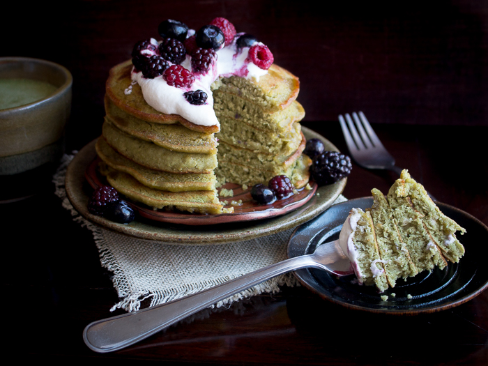 Matcha pancakes are slices showing the bite shot on a fork on a black plate. 