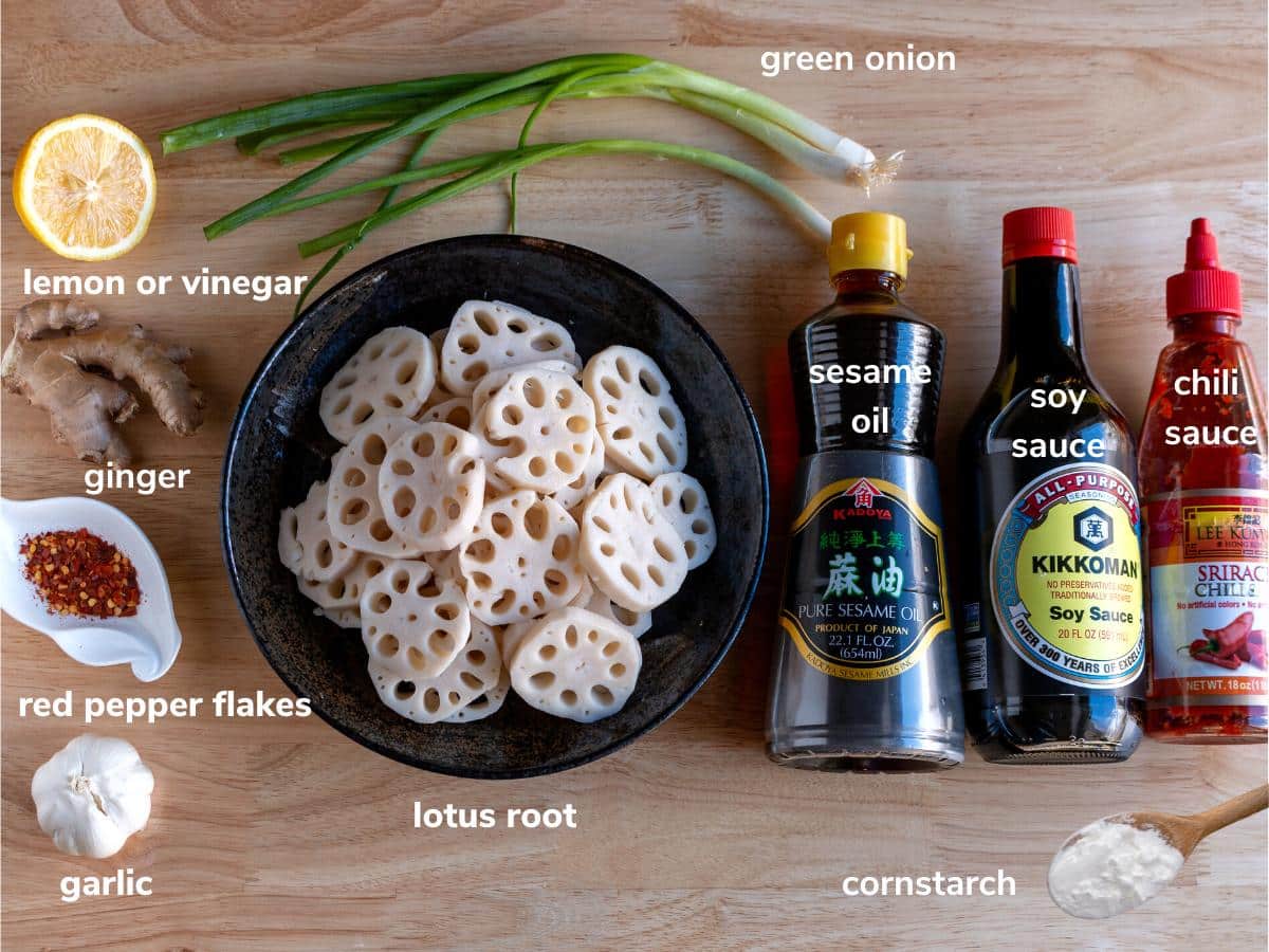 Ingredients to make a spicy lotus root stir fry laid out on a wooden table.