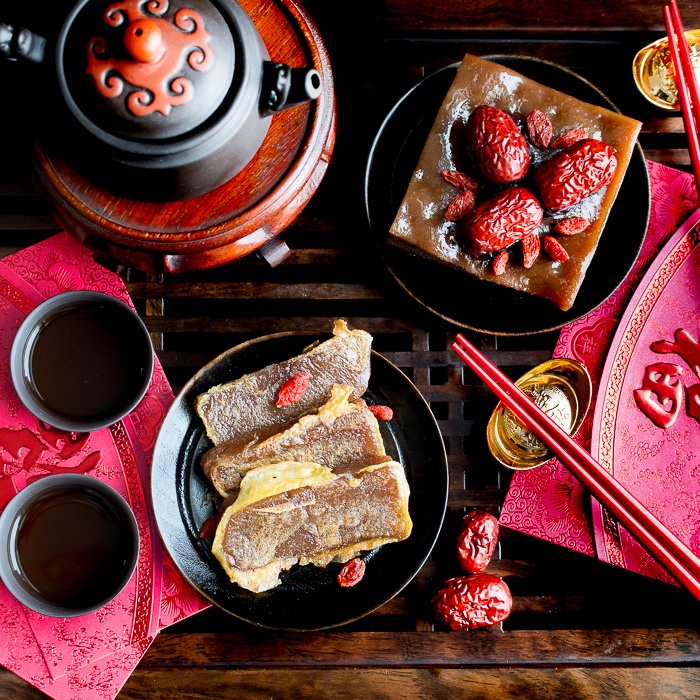 Sweet sticky rice Chinese new year cakes  that have been sliced and fried in egg with puerh tea and red packets. 