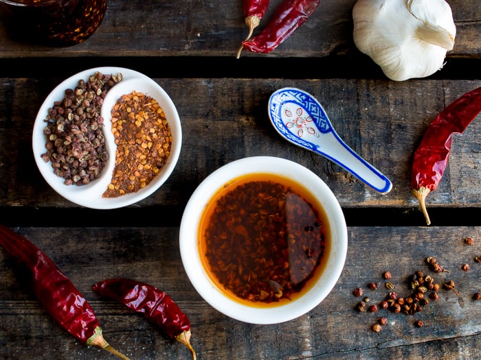 Top down shot of garlic chili oil in a bowl and all the ingredients to make it surrounding the bowl.