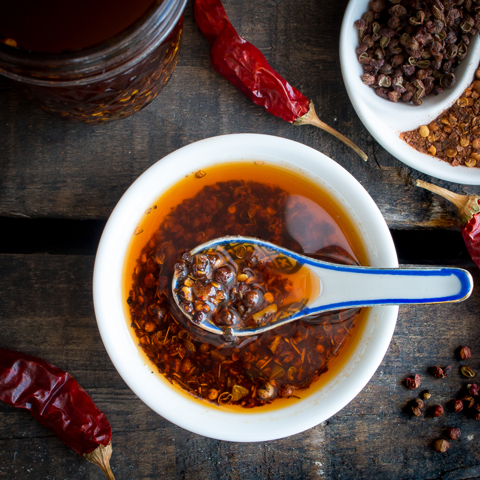 Scoop of Homemade Sichuan Garlic Chili Oil in a white bowl with a blue and white Chinese spoon.