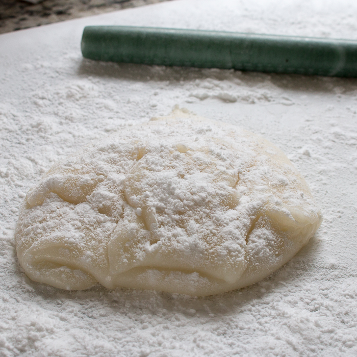 Fresh cooked mochi flour on a white board with a rolling pin. 