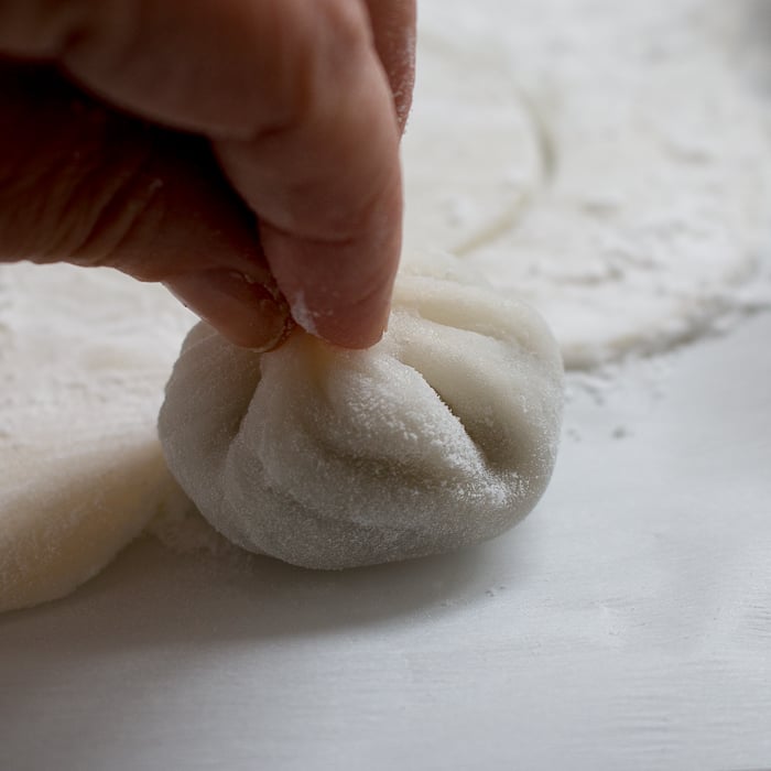 Fresh Daifuku Mochi getting rolled up in hands. 