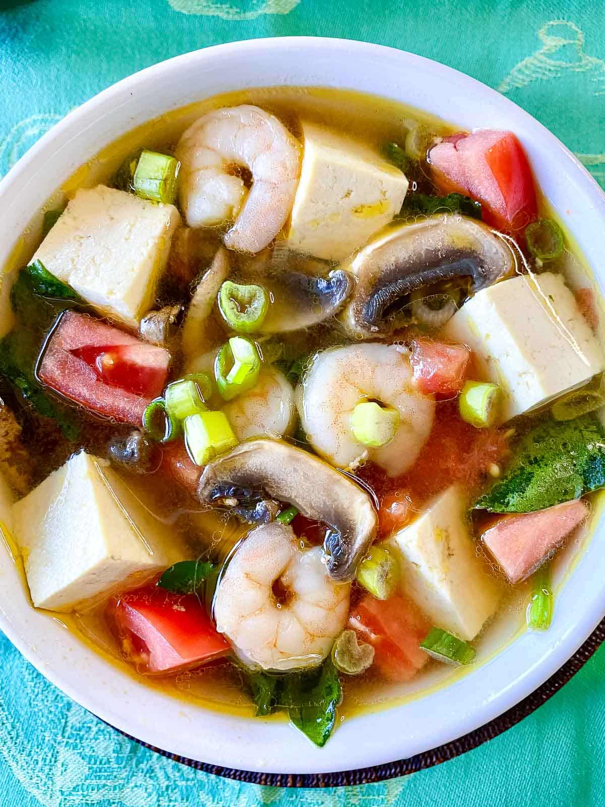 Top down view of the the shrimp and tofu soup showing all of the veggies and savory broth.