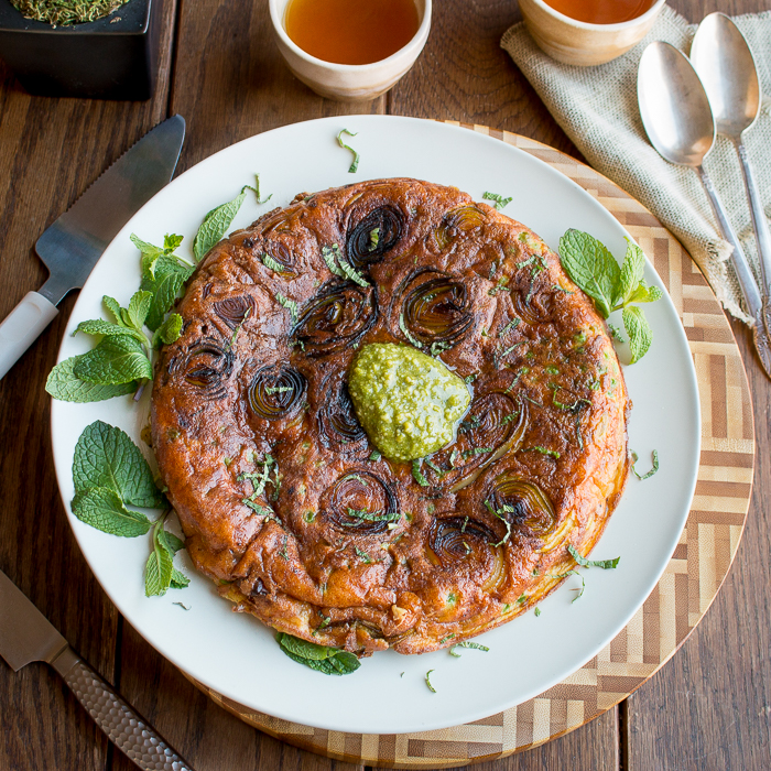 Parmesan Leek Frittata garnished with pesto and fresh herbs.