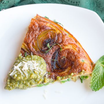 Stove Top Parmesan Leek Frittata slice on a shite plate with a dollop of pesto on top.