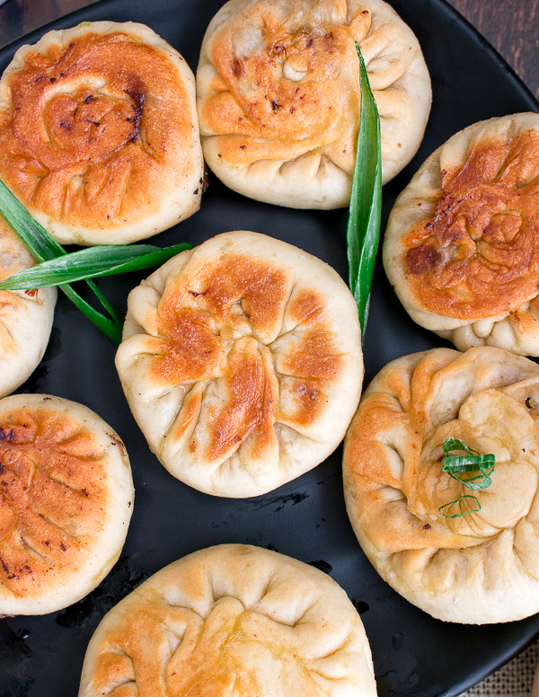 Beef Bao on a black plate showing the crispy pan fried edges. 