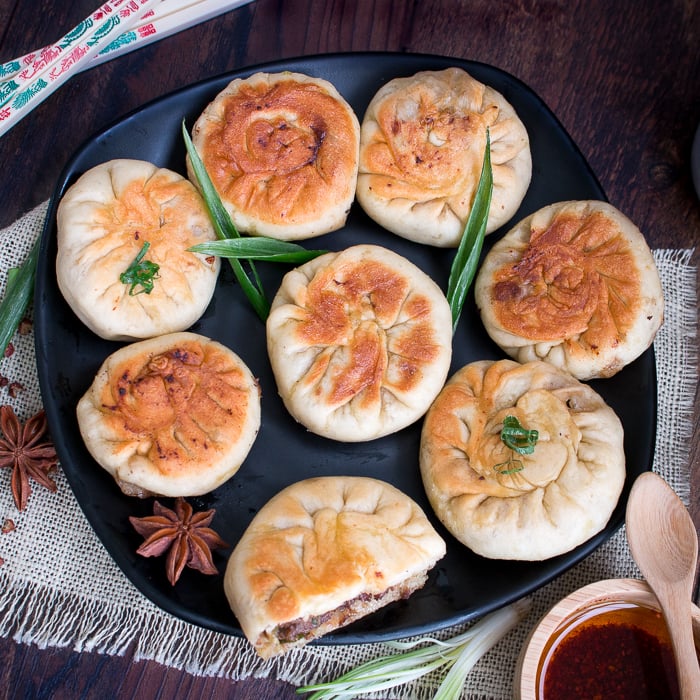 Spicy Pan Fried Beef Bao on a black plate with fresh green onions.