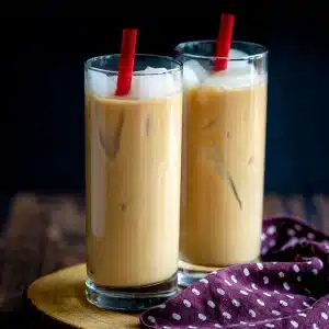 coconut iced chai lattes on a wooden board.