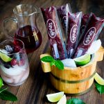 Berry Wine Pops in a wooden ice container with a side of frozen berries and Moscato wine.