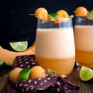 Cantaloupe lime agua fresca garnished with balls of melon and lime.