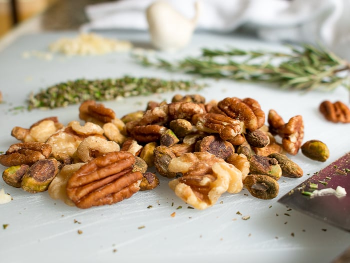 Raw nuts and fresh herbs on a cutting board. 