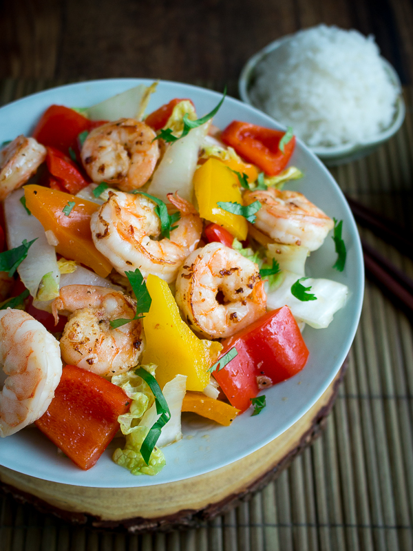 Shrimp, cabbage and peppers stir fry in a blue Chinese bowl.