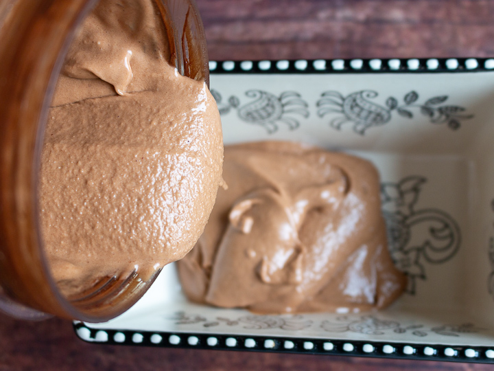 Mocha Banana Ice Cream soft serve getting poured into a black and white ceramic bowl.