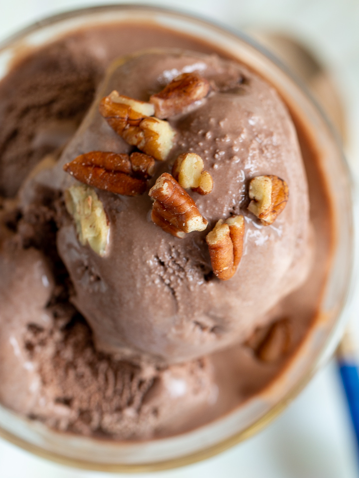 Triple scoop of Mocha banana ice cream in a glass bowl topped with toasted pecans.