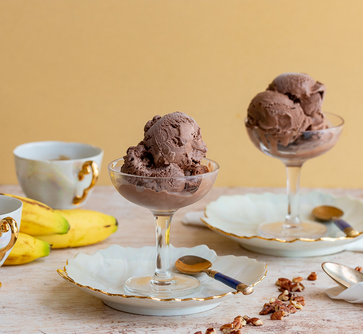 2 cups of chocolate pudding in glass dishes with a dollop of coconut whipped topping and a holiday scene.