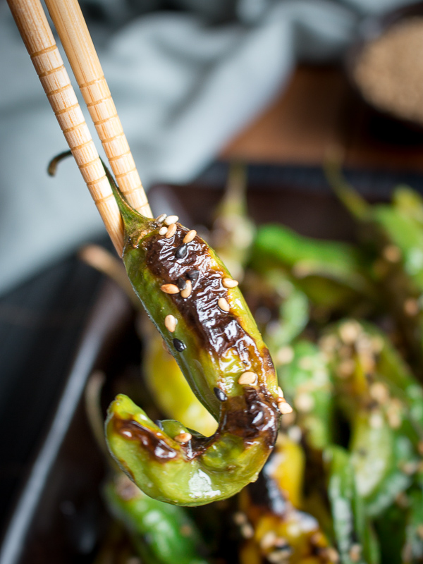 Holding a shishito pepper with chopsticks.