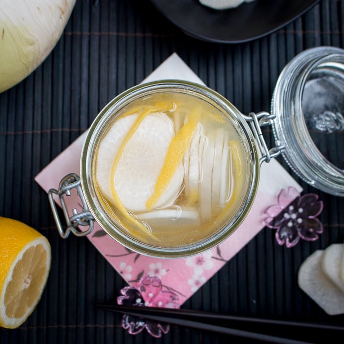 Lemon Diakon Radish Refrigerator Pickles in a jar with chopsticks on the side.