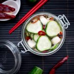 Spicy Garlic Cucumber Refrigerator Pickles in a glass jar with chili peppers.