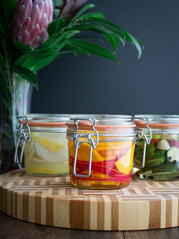 Daikon radish, beets and cucumber refrigerator pickles all laid out on a board. 