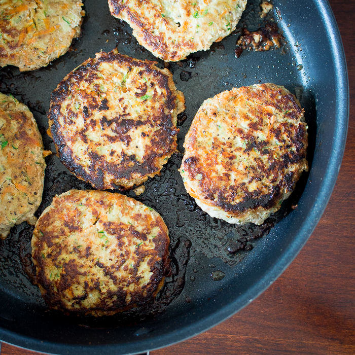 Turkey burgers getting fried up in a skillet pan.