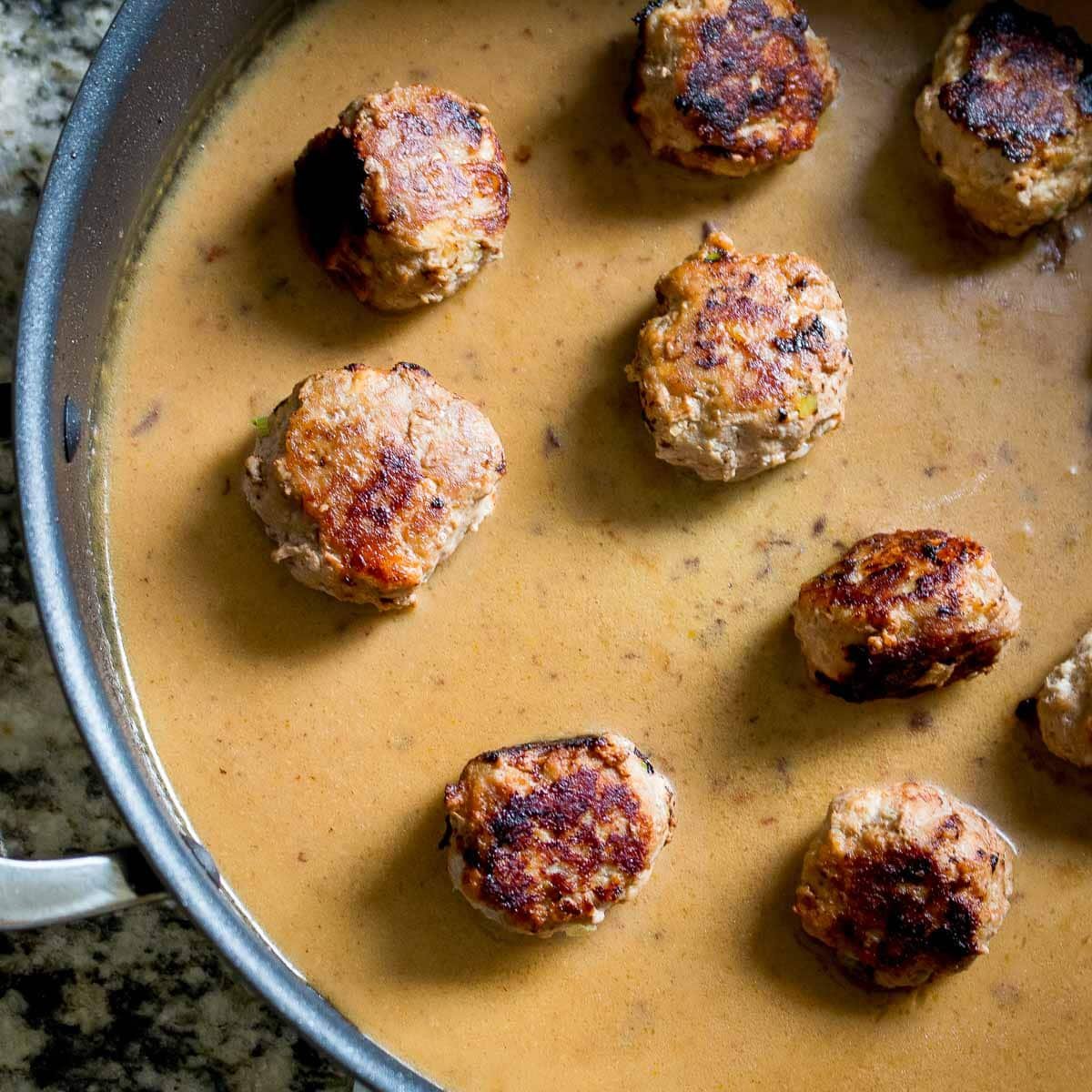 Thai low carb turkey meatballs put in the pan with the red curry sauce. 