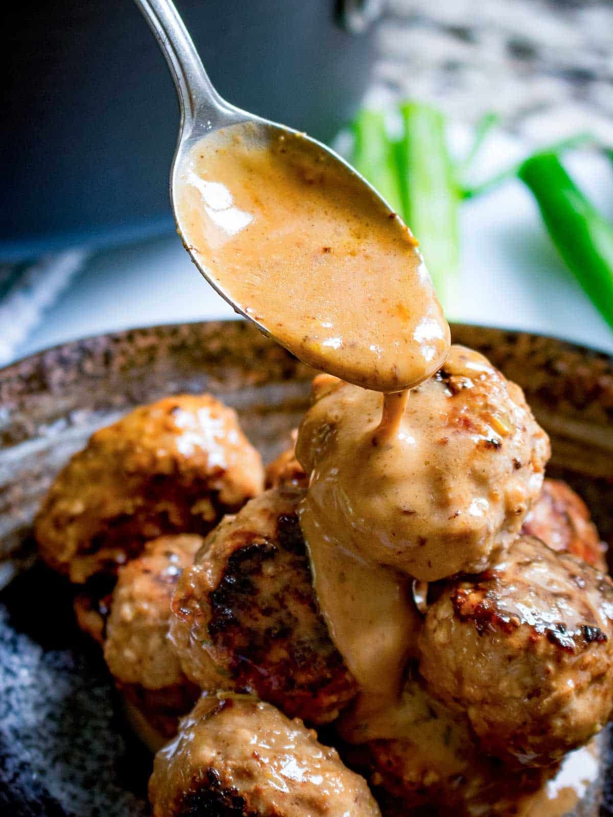 Coconut red curry sauce getting spooned over the turkey tofu meatballs. 