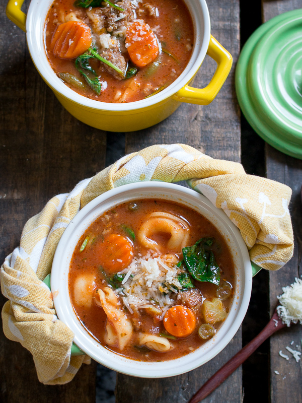 2 bowls of soup in little yellow and green mugs with matching napkins wrapped on the the handles.