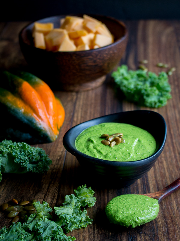 Kale pesto in a black bowl with a spoonful of it too.