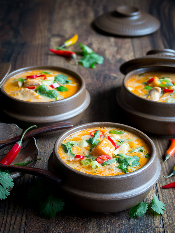 Creamy Thai Sweet Potato Chicken Soup with spoons in brown bowls with lids.