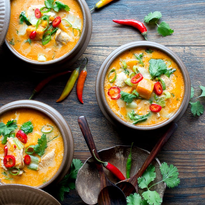 Creamy Thai Sweet Potato Chicken Soup in brown bowls garnish with chili peppers. 